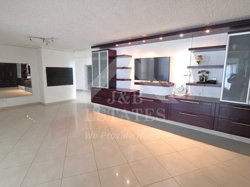 Spacious living area featuring large format floor tiles, extensive built-in dark wood cabinetry, and integrated display shelving.