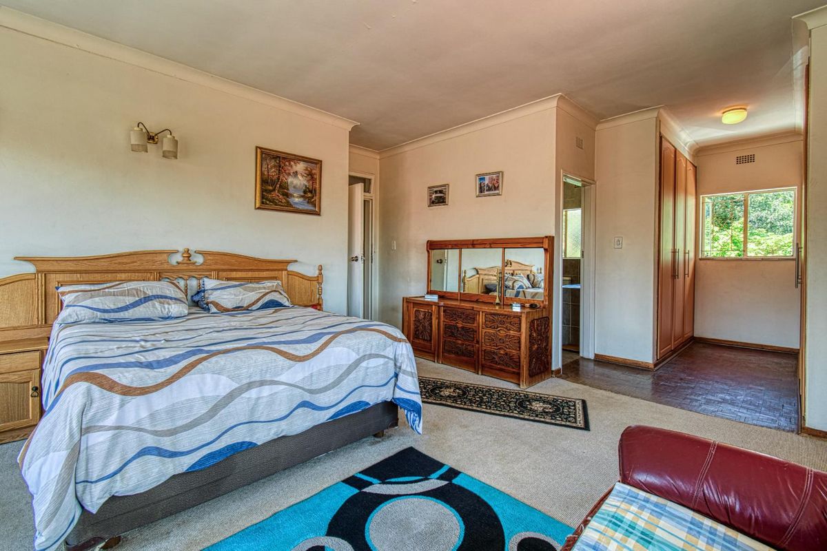 Spacious bedroom featuring built-in wooden wardrobes, carpeted flooring, and an en-suite bathroom access.