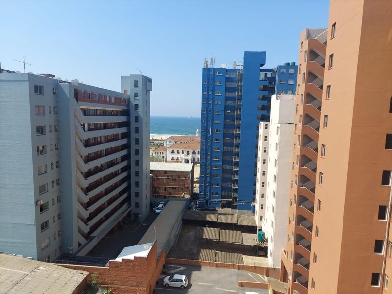 An elevated urban view overlooking surrounding apartment buildings with a glimpse of the ocean in the distance.