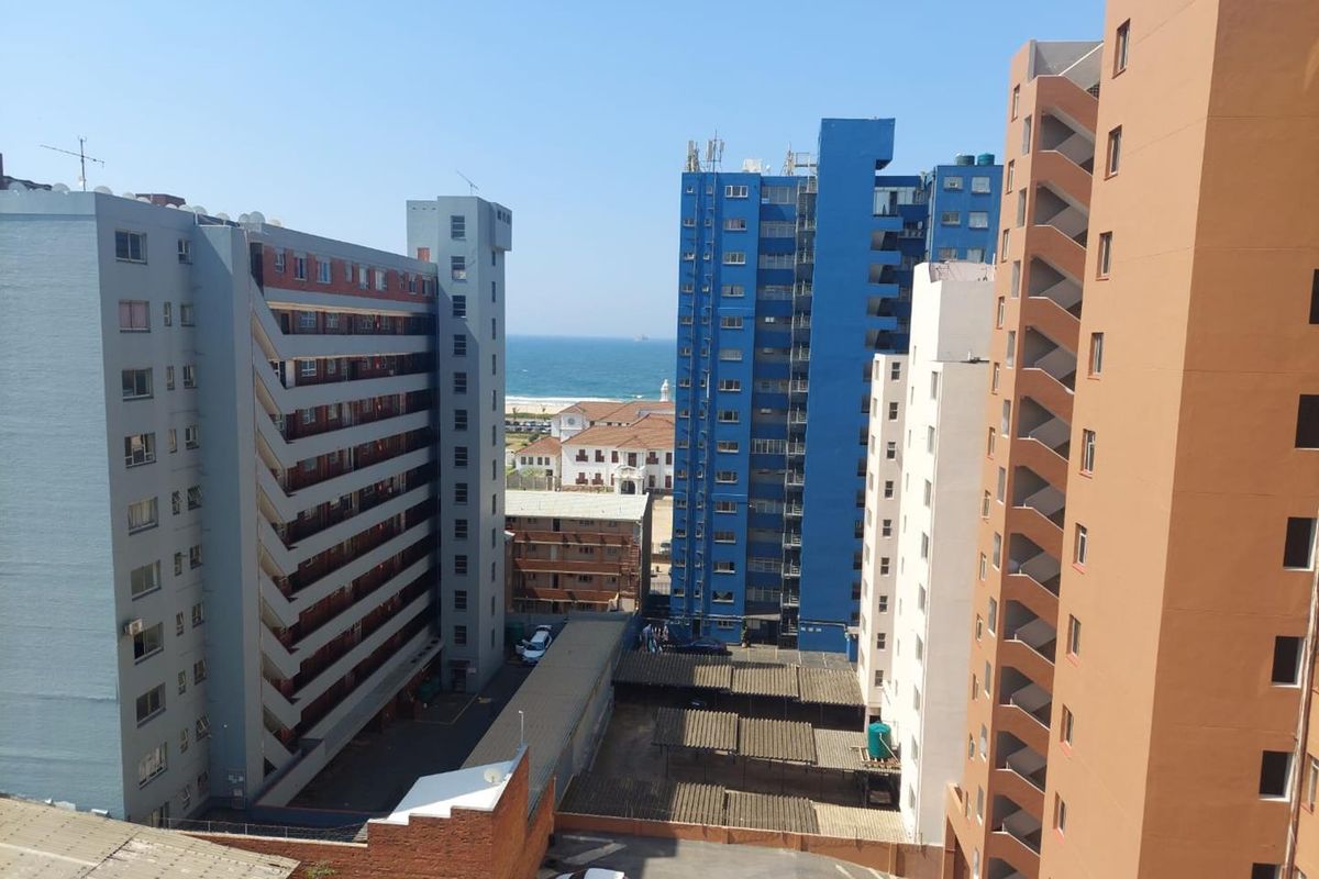 An elevated urban view overlooking surrounding apartment buildings with a glimpse of the ocean in the distance.