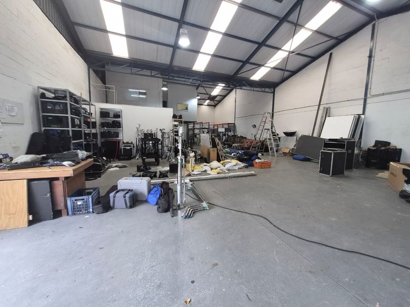 Spacious industrial warehouse unit featuring high ceilings with exposed steel trusses, translucent roof panels for natural light, and durable concrete flooring.