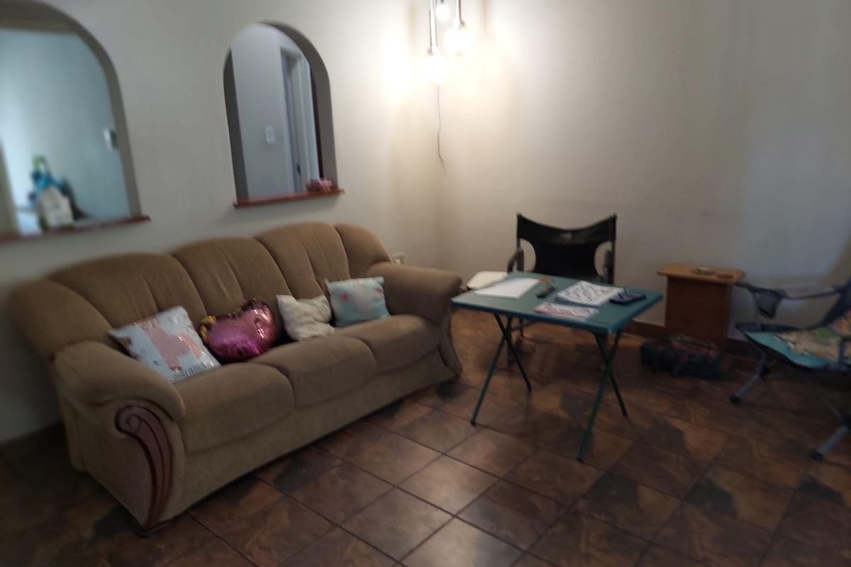 A living room featuring tiled flooring and two distinctive arched wall openings, providing a view into adjacent spaces.