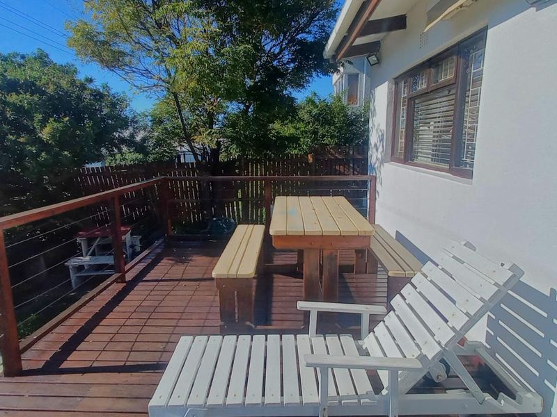 An elevated timber deck patio featuring a wooden balustrade with steel cable railings, providing an outdoor entertainment space adjacent to the main dwelling.