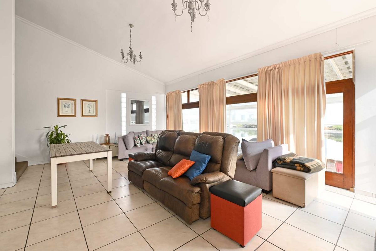 Spacious living room featuring vaulted ceilings, tiled flooring, and large windows with direct access to the outdoor area.