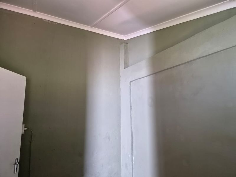 An empty interior space featuring painted walls and a standard door, requiring cosmetic updates to improve the overall finish.