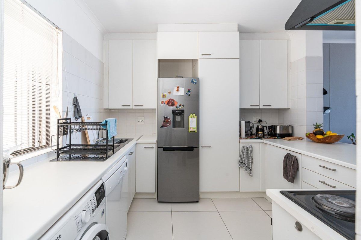 A functional kitchen featuring white built-in cabinetry, tiled backsplash, ceramic flooring, and integrated appliances, offering a clean and practical layout.