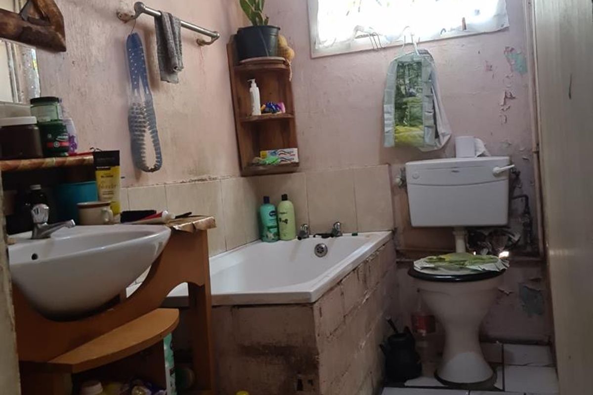 A dated bathroom featuring a standard bathtub, pedestal basin, and toilet, requiring significant cosmetic renovation and repair to wall finishes.