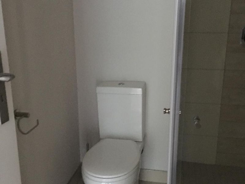 A functional bathroom featuring a standard toilet and a separate shower enclosure with tiled walls.