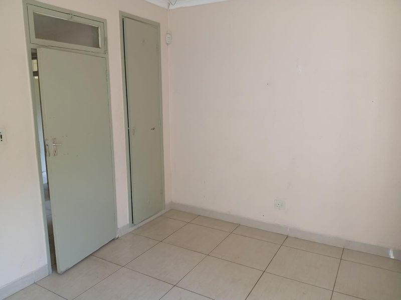 An empty bedroom featuring neutral tiled flooring and a built-in cupboard, providing a blank canvas for personalization.