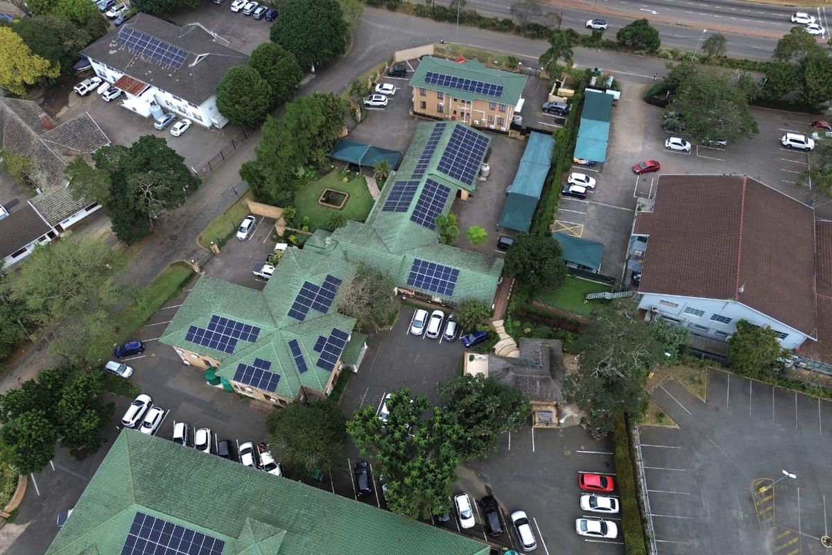 Aerial view of the office complex featuring multiple buildings with extensive rooftop solar panel installations, paved parking areas, and landscaped grounds.
