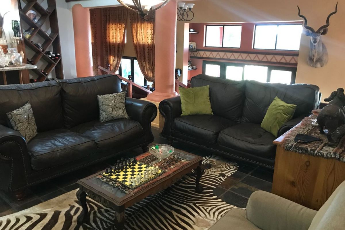 Spacious living area featuring decorative columns, slate tile flooring, and built-in wine storage shelving.