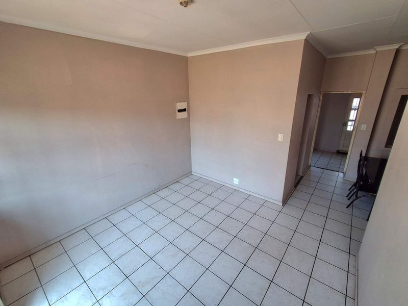 An empty living area featuring tiled flooring, cove cornicing, and a neutral wall finish, providing a blank canvas for interior design.