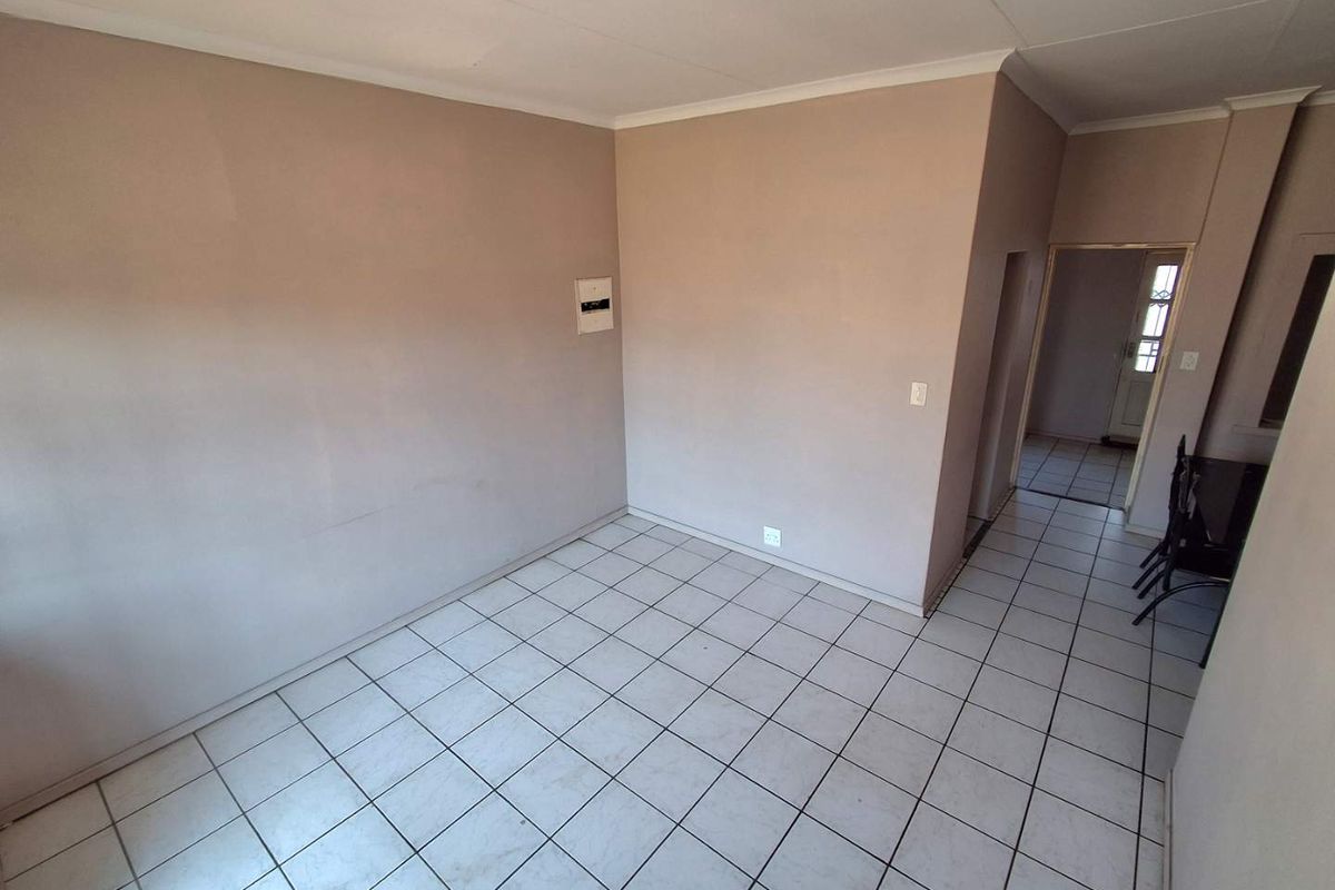 An empty living area featuring tiled flooring, cove cornicing, and a neutral wall finish, providing a blank canvas for interior design.