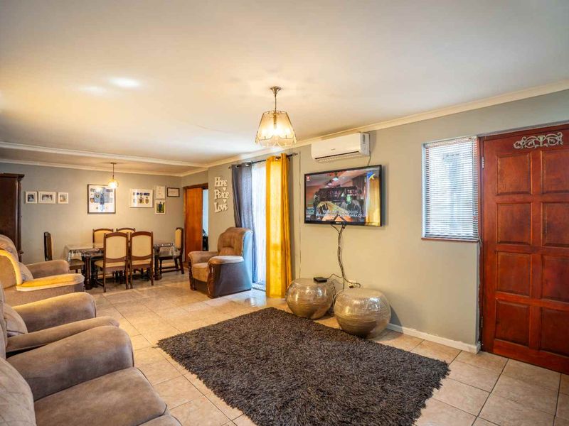 Spacious open-plan living and dining area featuring tiled flooring, split-system air conditioning, and direct access through a solid timber entrance door.