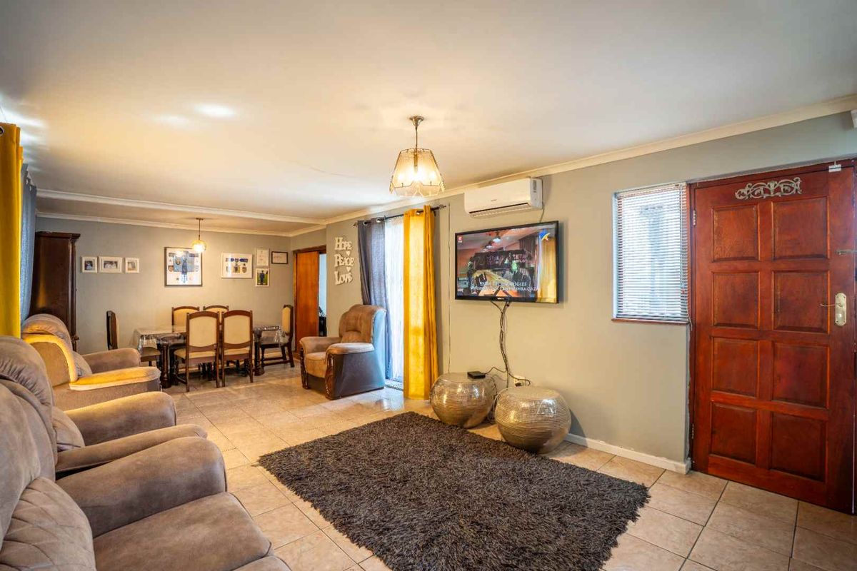 Spacious open-plan living and dining area featuring tiled flooring, split-system air conditioning, and direct access through a solid timber entrance door.