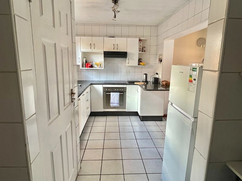 A functional kitchen featuring white built-in cabinetry, a built-in oven and hob, tiled walls, and tiled flooring.