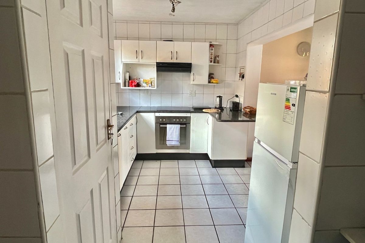 A functional kitchen featuring white built-in cabinetry, a built-in oven and hob, tiled walls, and tiled flooring.