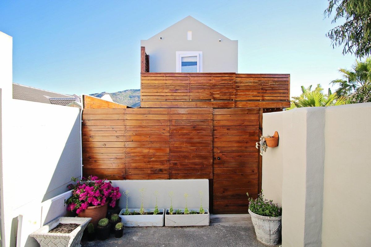 A private rear courtyard featuring a timber privacy screen, a secure wooden gate, and a paved patio area.