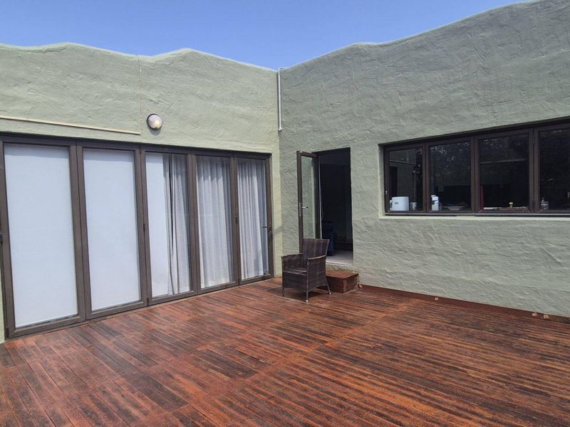 Spacious outdoor timber deck featuring bi-fold doors and large windows, providing a seamless transition between indoor and outdoor living areas.