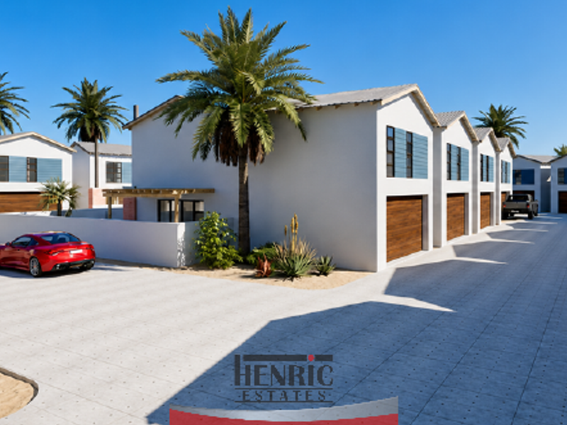 A modern townhouse complex featuring a paved driveway, multiple garage access points, and clean architectural lines in a well-maintained estate setting.