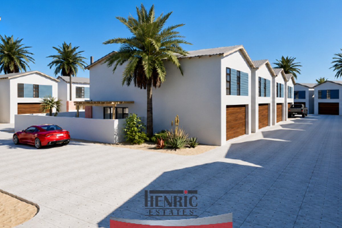 A modern townhouse complex featuring a paved driveway, multiple garage access points, and clean architectural lines in a well-maintained estate setting.