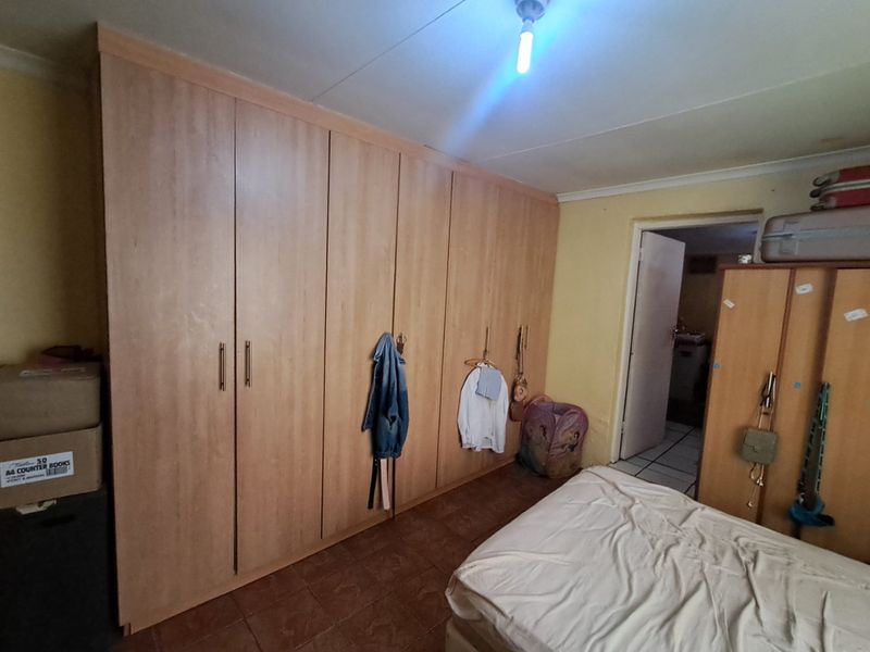 A bedroom featuring extensive built-in wooden wardrobes and tiled flooring, providing ample storage space.