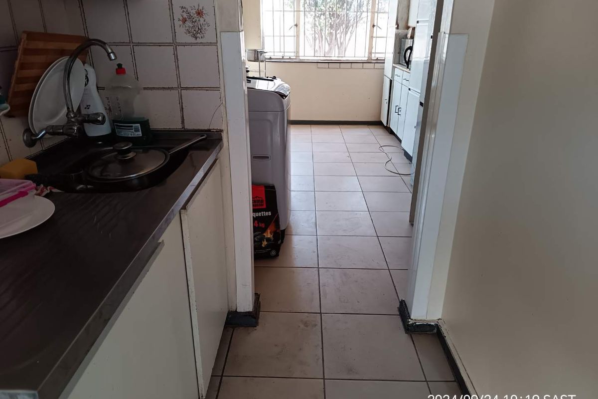 A functional kitchen area featuring built-in cabinetry, a stainless steel sink, and tiled flooring, requiring cosmetic updates to modernize the space.