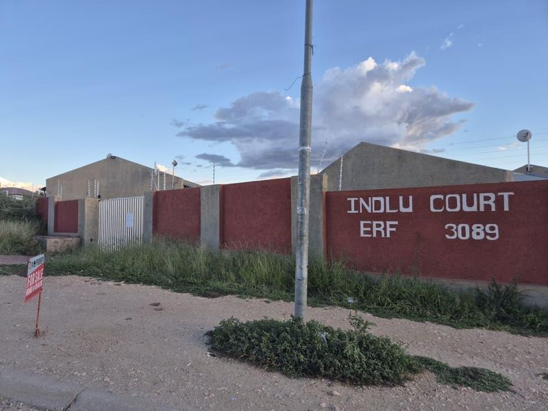 Street view of Indlu Court showing the perimeter wall, security gate, and electric fencing from the roadside.