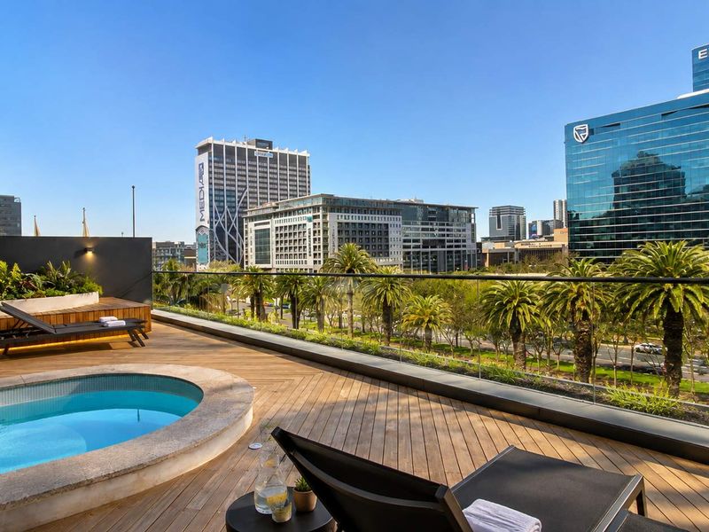 Spacious balcony featuring timber decking, a private plunge pool, and a glass balustrade offering expansive urban views.