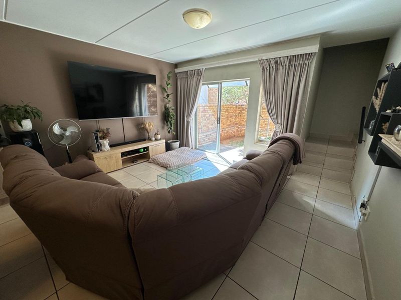 A comfortable living room featuring tiled flooring and a sliding glass door that provides direct access to the outdoor patio area.