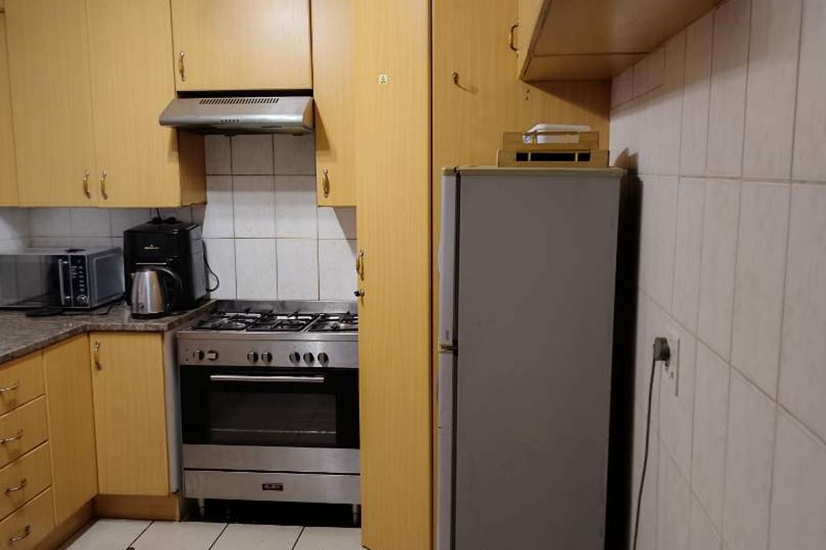 A functional kitchen featuring light wood cabinetry, a gas stove with extractor fan, tiled backsplash, and tiled flooring.