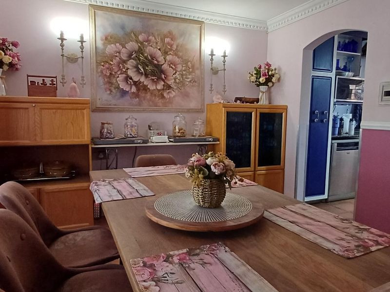A traditional dining room featuring crown molding, wall sconces, and an arched entryway leading to an adjacent kitchen area.