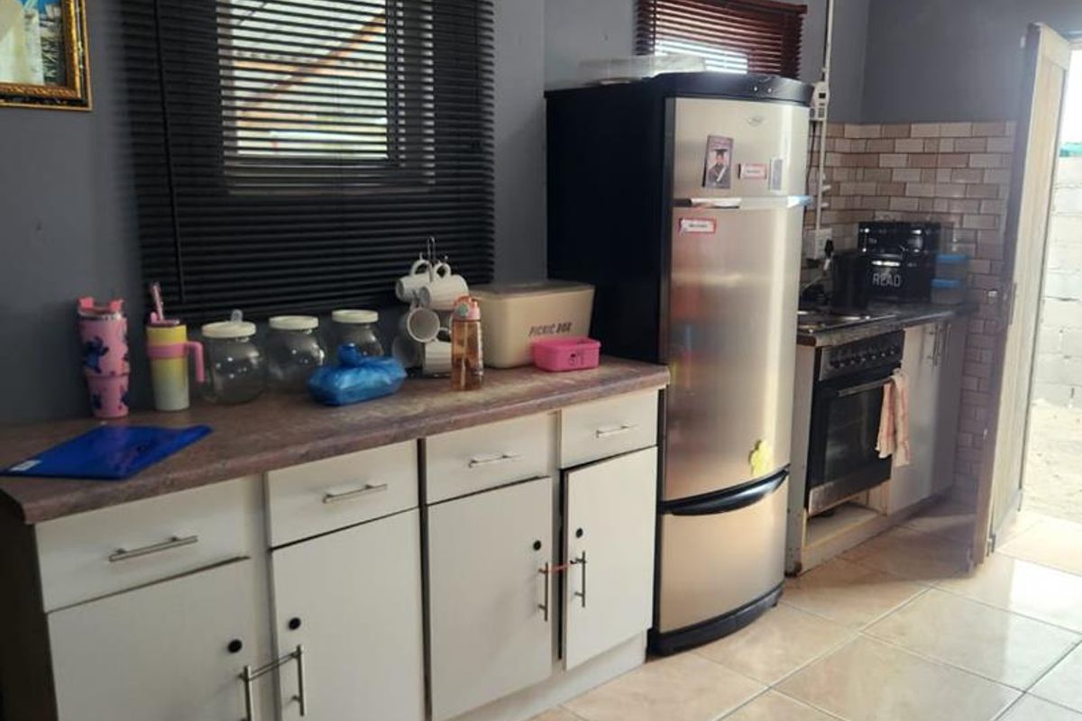 A functional kitchen featuring built-in cabinetry, laminate countertops, and a freestanding stove, with tiled flooring and visible ceiling water damage.