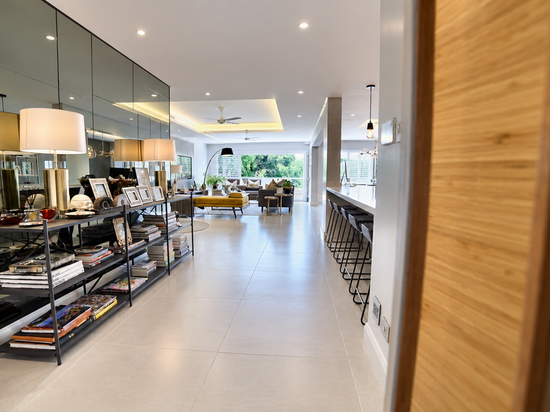Spacious open-plan living area featuring large format floor tiles, a mirrored feature wall, recessed lighting, and a modern kitchen island with breakfast bar seating.