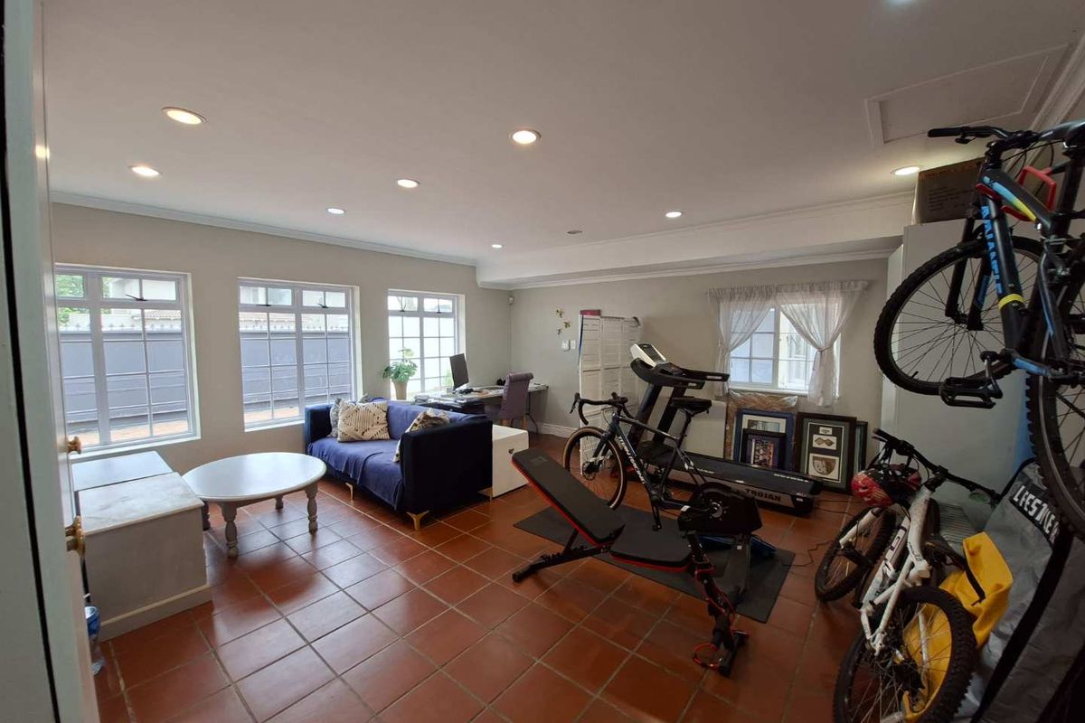 A spacious living area featuring terracotta floor tiles, recessed downlighting, and large multi-pane windows providing ample natural light.