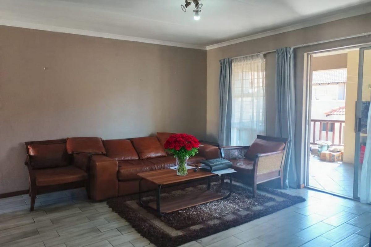 A living room featuring tiled flooring and a sliding glass door providing access to an outdoor patio area.