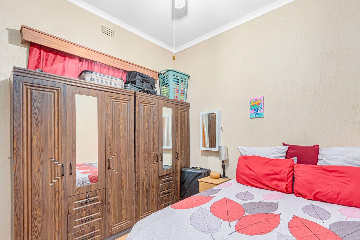 A bedroom featuring a large built-in wardrobe with mirrored panels and a ceiling fan, providing functional storage and climate control.