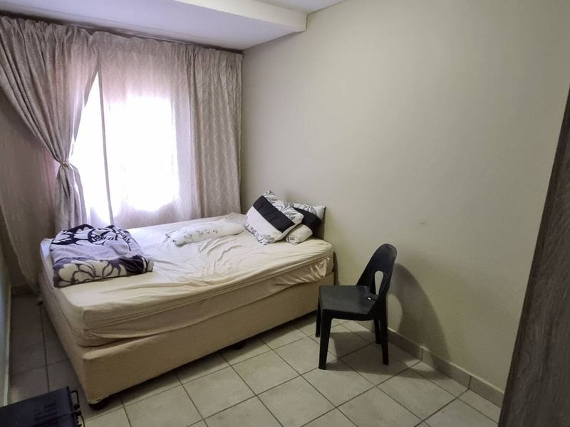 A simple bedroom featuring tiled flooring and a window with curtain rails, providing a functional space for rest.