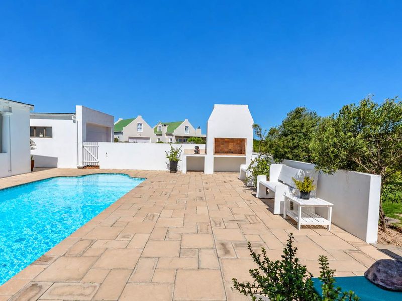 Outdoor pool area featuring a paved patio, built-in braai, and surrounding boundary walls, perfect for entertaining.