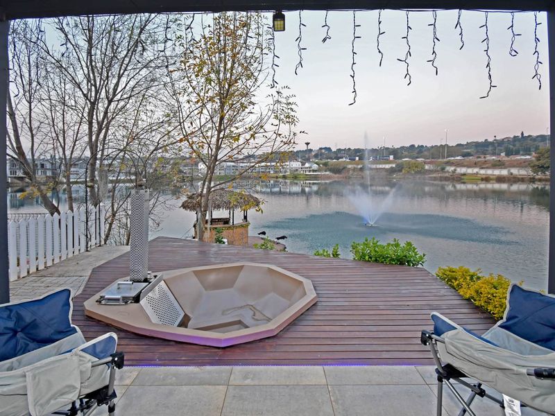 Covered patio featuring timber decking, a sunken fire pit, and direct views over the lake and fountain.