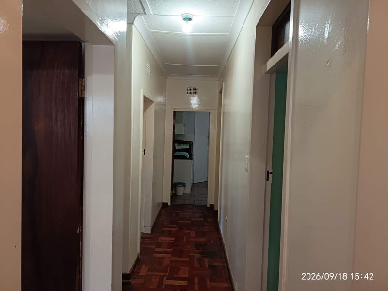 A functional hallway featuring traditional parquet flooring and access to multiple rooms, providing a central circulation space within the home.