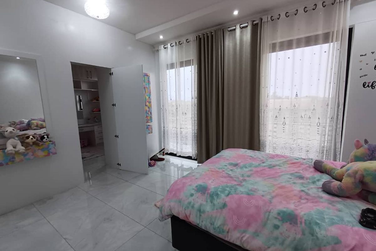 A well-maintained bedroom featuring polished tile flooring, recessed ceiling lighting, and a walk-in closet area with built-in cabinetry.