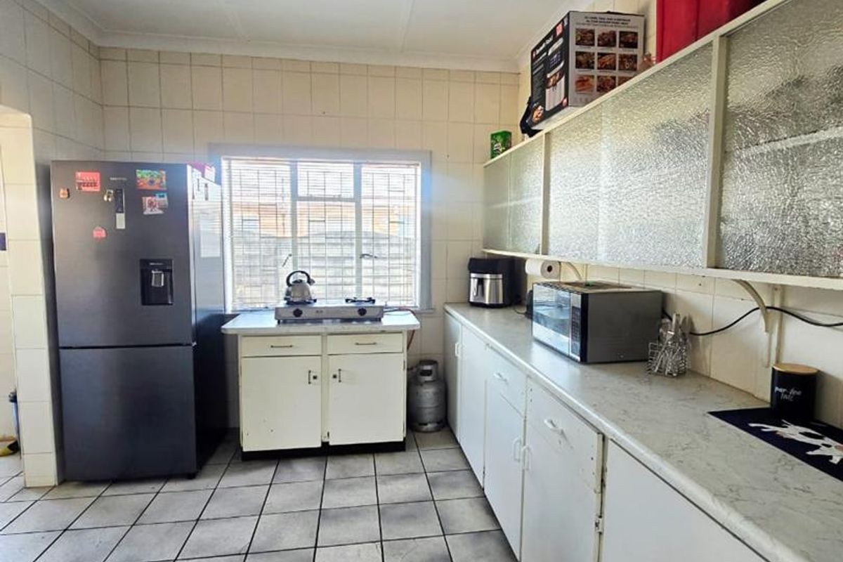 A functional kitchen featuring tiled flooring, extensive built-in cabinetry, and laminate countertops, currently showing signs of wear and requiring cosmetic updates.