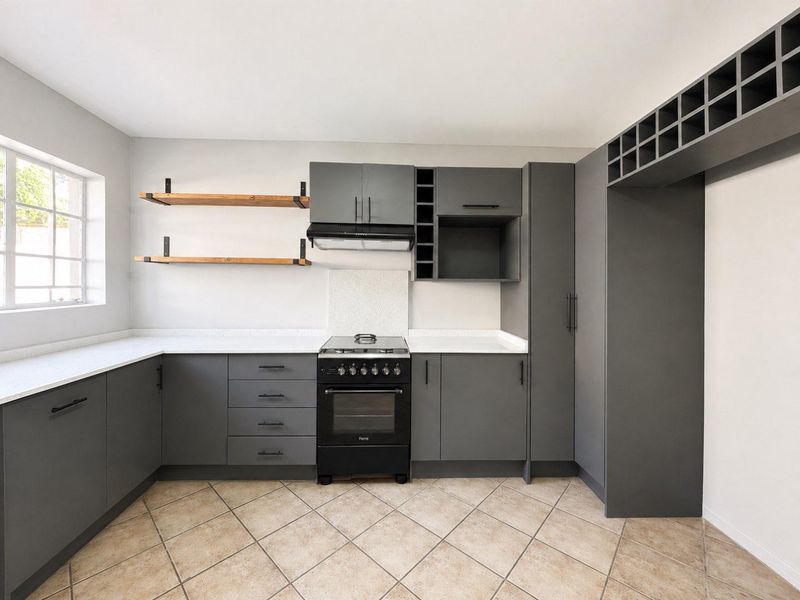 Modern kitchen featuring dark grey cabinetry, stone countertops, a freestanding stove with extractor fan, and open shelving, finished with tiled flooring.