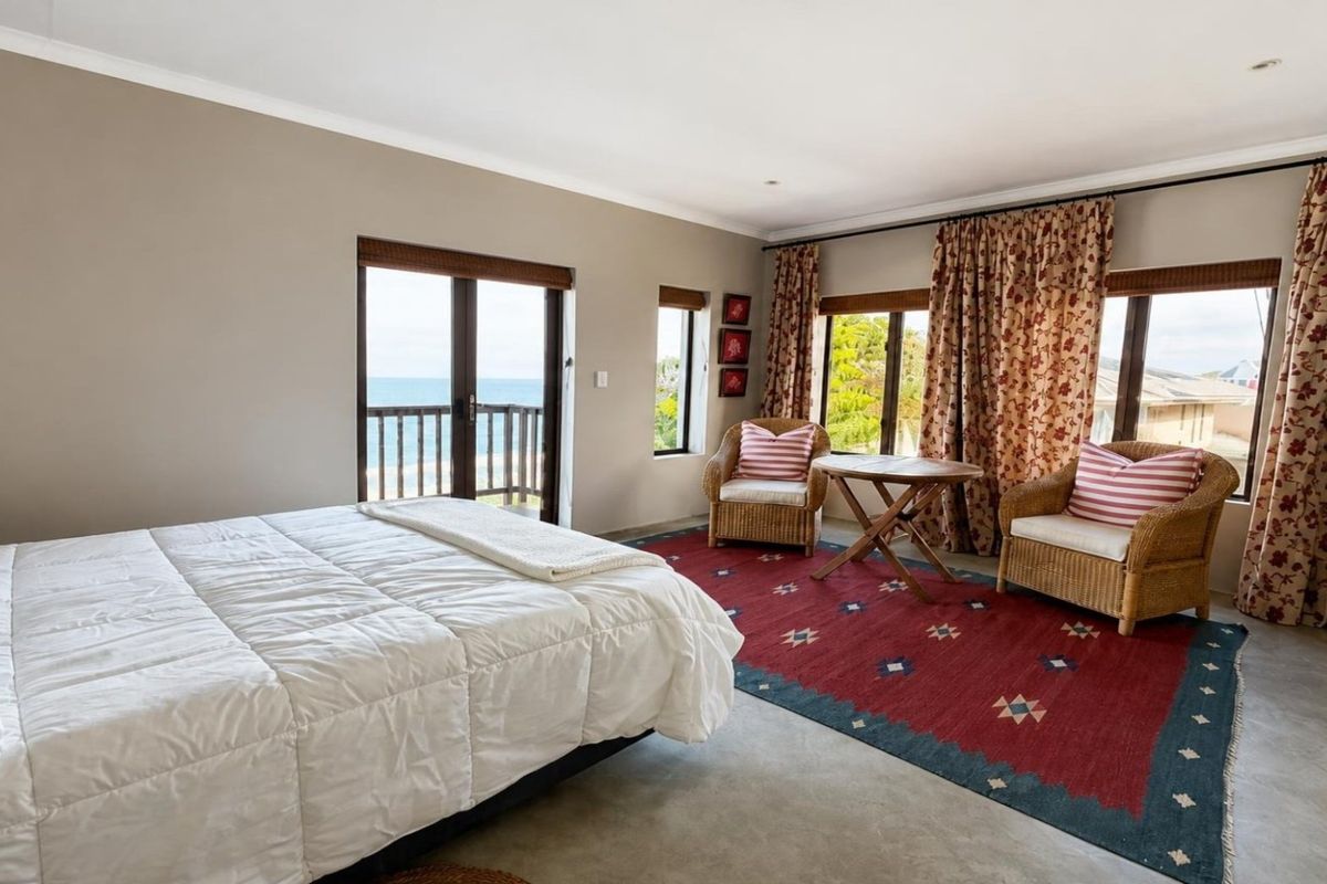 Spacious bedroom featuring concrete flooring, recessed lighting, and sliding glass doors opening to a balcony with ocean views.