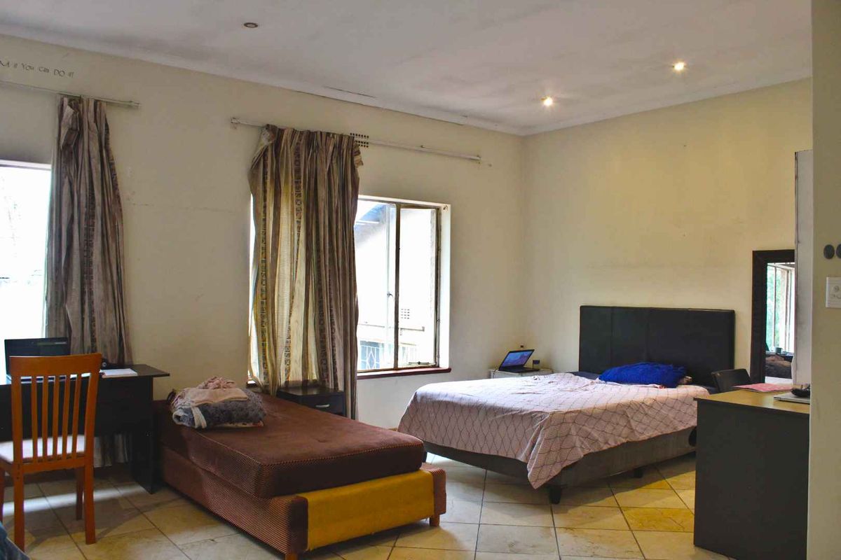 Spacious bedroom featuring tiled flooring and recessed downlighting, offering a functional layout with natural light from multiple windows.
