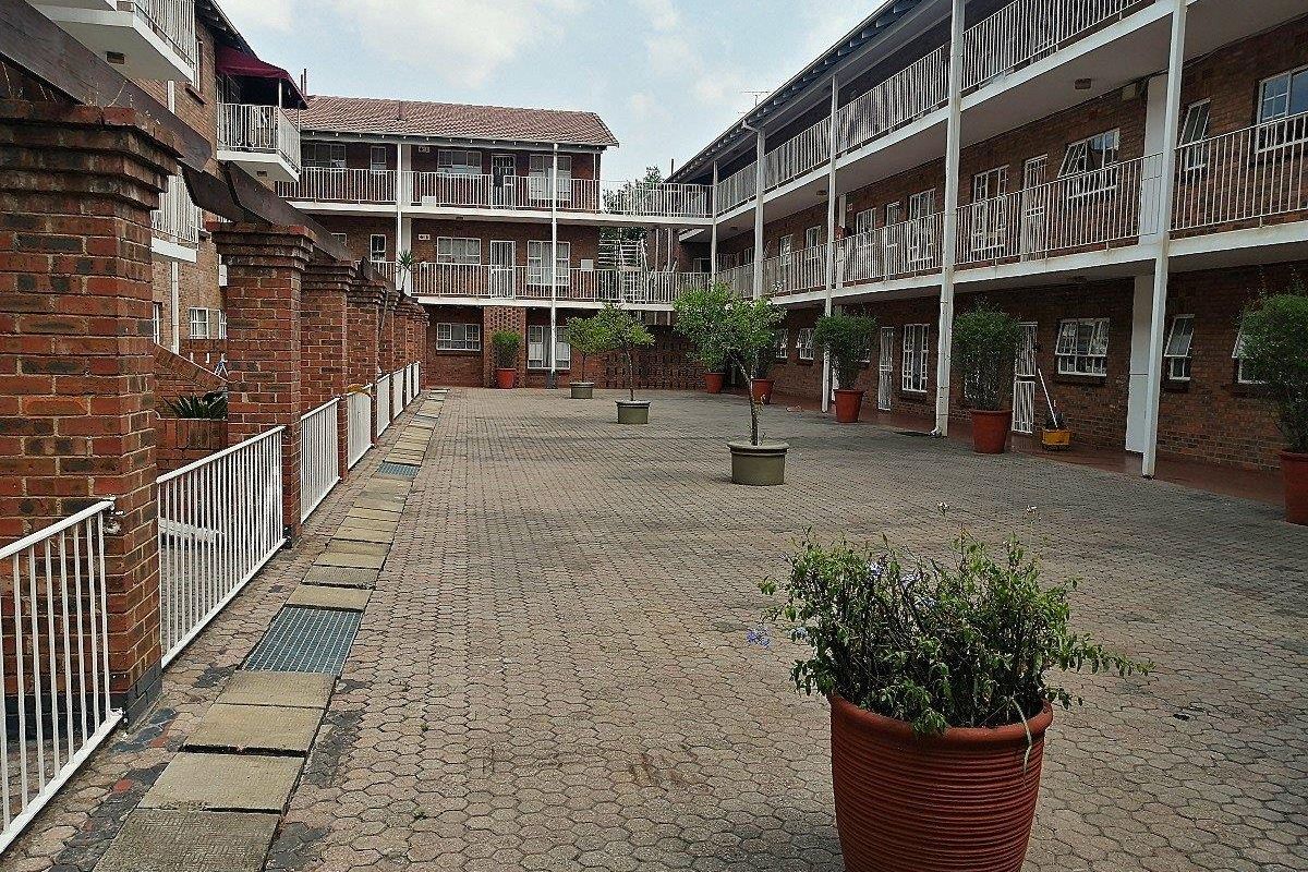 A paved communal courtyard area within an apartment complex, featuring brick facade buildings with multi-level metal balconies and walkways.