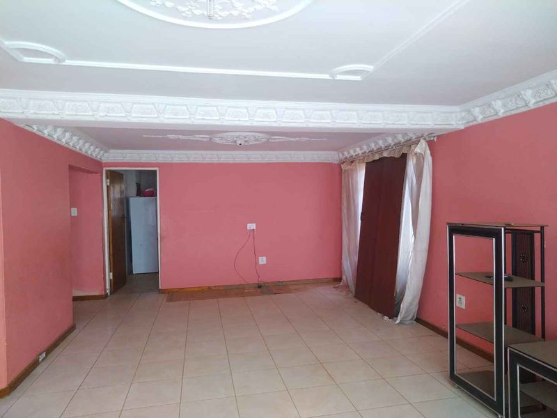 Spacious living area featuring decorative ceiling cornices, ceiling roses, and tiled flooring, offering a blank canvas for renovation and interior design updates.