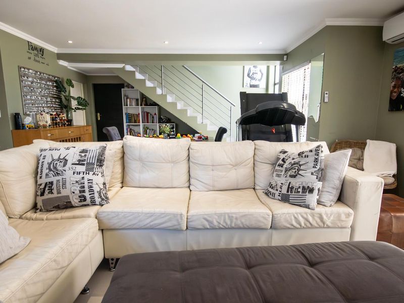 Spacious living area featuring a modern staircase with metal balustrade, recessed lighting, and a wall-mounted air conditioning unit.