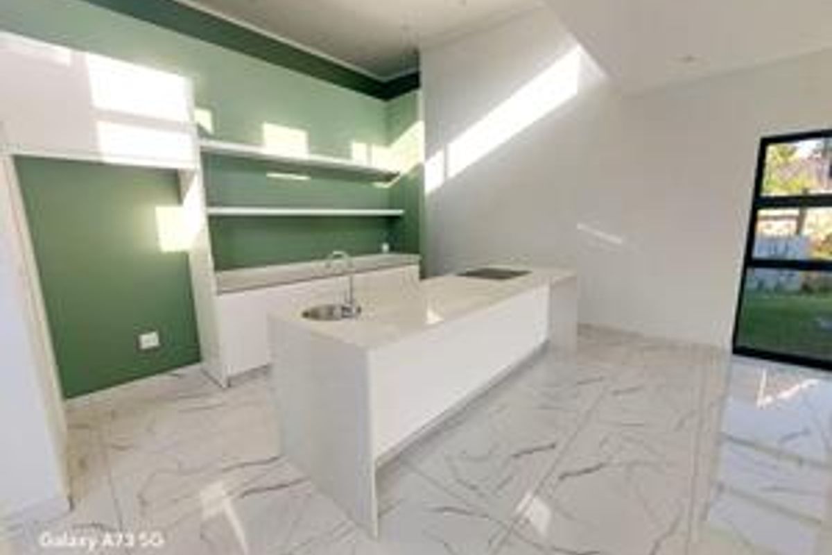 Modern, minimalist kitchen featuring a central island with integrated hob and sink, open shelving, and sleek marble-look floor tiles in a bright, open space.
